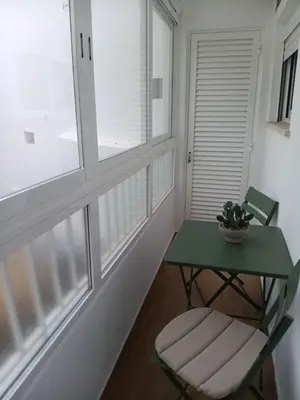 a green table and a chair in a room with windows at Casa Tapada do Bento III- Albufeira in Albufeira