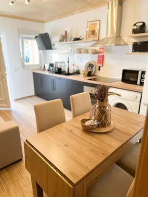 a kitchen with a wooden table with chairs and a kitchen with a counter at Casa Rústica em Loulé - Karmea's Houses in Loulé
