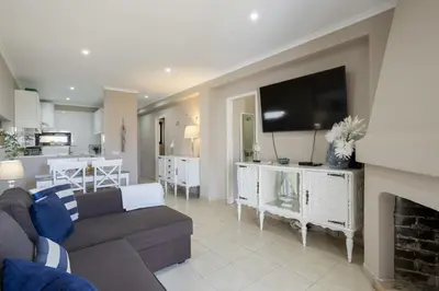 a living room with a couch and a flat screen tv at Forte Beach Retreat - 2BR Apartment with Terrace & AC in Caliços