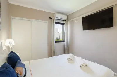a person laying on a bed with their feet on a television at Forte Beach Retreat - 2BR Apartment with Terrace & AC in Caliços