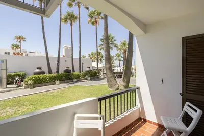 a balcony with two chairs and palm trees at Forte Beach Retreat - 2BR Apartment with Terrace & AC in Caliços