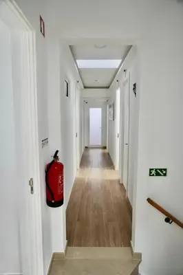 a long hallway with a red fire extinguisher on the wall at Casa Tapada do Bento II- Albufeira in Albufeira