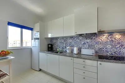 a white kitchen with white cabinets and a sink at Atlantic Horizon by Seareen in Albufeira