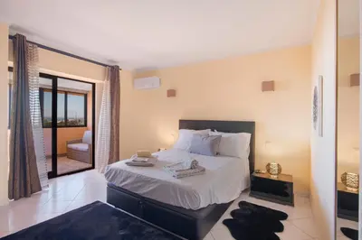 a bedroom with a large bed and a balcony at Apartamento Perfeito in Albufeira