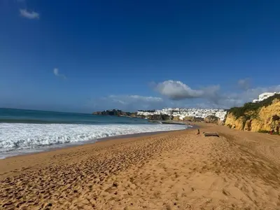a beach with a person walking on the sand at Apartamento Perfeito in Albufeira