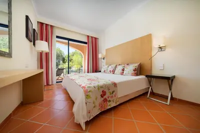 a hotel room with a bed and a balcony at Vila Sol F5 W Golf and Pool Apartment in Vilamoura