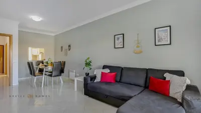 a living room with a black couch with red pillows at Greice Homes - T2 - JV - Vilamoura Centre in Quarteira