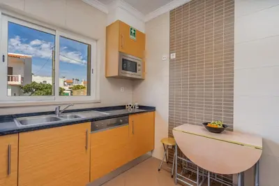 a kitchen with wooden cabinets and a sink and a window at Casa Vista Brejos in Albufeira