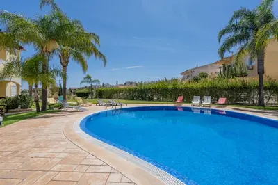 a swimming pool with chairs and palm trees at Casa Vista Brejos in Albufeira