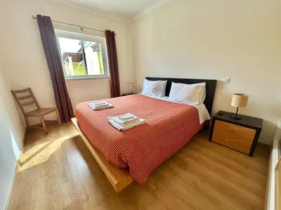 a bedroom with a bed with a red comforter and a window at Casa Vista Brejos in Albufeira