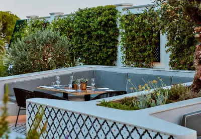 a patio with two tables with wine glasses on it at Dunas Douradas Beach Club in Vale do Lobo
