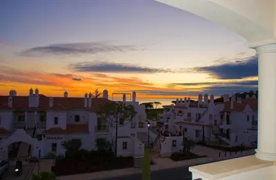 a view of a city at sunset from a building at Dunas Douradas Beach Club in Vale do Lobo