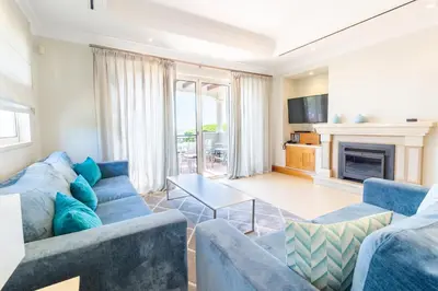 a living room with a blue couch and a fireplace at Dunas Douradas Beach Club in Vale do Lobo