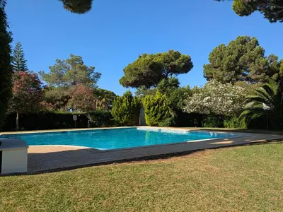 a swimming pool in a yard with trees in the background at Solar dos Pinheiros T3 in Vilamoura