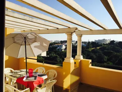 a table with an umbrella and chairs on a balcony at Albufeira Luxury Villa in Albufeira