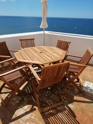 a wooden table and chairs with a view of the ocean at Breathtaking BeachFront House in Albufeira