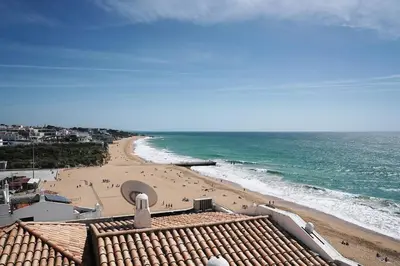 a view of a beach with people on the sand at Breathtaking BeachFront House in Albufeira