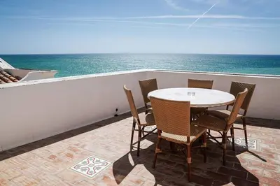 a table and chairs on a balcony with the ocean at Breathtaking BeachFront House in Albufeira
