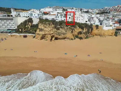 a view of a beach with a red door on a cliff at Breathtaking BeachFront House in Albufeira
