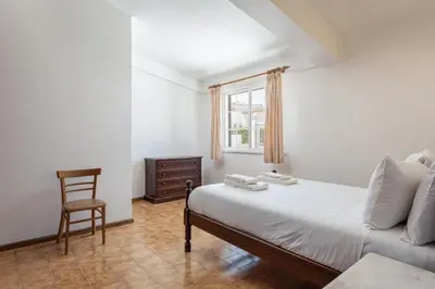 a bedroom with a bed and a chair and a window at Vila Coelho - City center with pool by HD in Vale de Pedras