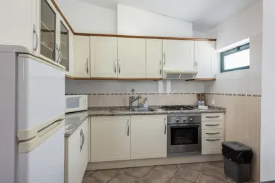 a kitchen with white cabinets and a sink at Vila Coelho - City center with pool by HD in Vale de Pedras