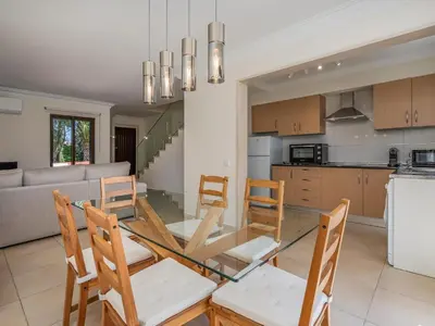a kitchen and dining room with a glass table and chairs at Duplex T2 com terraço e BBQ em Vilamoura in Quarteira