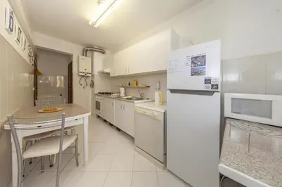 a kitchen with white appliances and a table and chairs at A02 - Casa Topazio in Quarteira in Quarteira