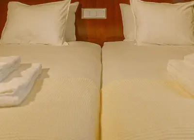 two beds in a hotel room with white sheets and pillows at Fly House Faro in Faro