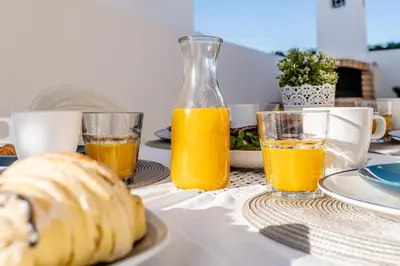 a table with two glasses of orange juice and a loaf of bread at Pet-Friendly with Private Pool Close to the Beach in Galé