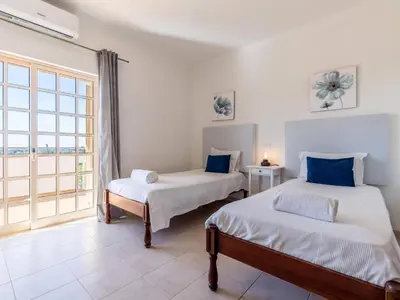 a bedroom with two beds and a large window at Villa Paradis Paraiso com piscina privada em Albufeira in Albufeira