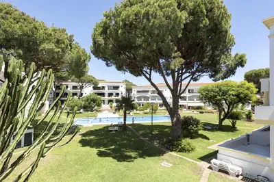 an apartment with a swimming pool and trees at NEW! Vilamoura Garden View in Quarteira