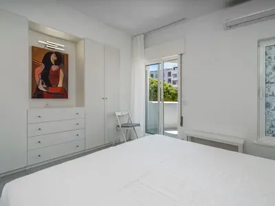 a white bedroom with a large bed and a painting at Algarsol 1bdr apartment near the beach in Quarteira