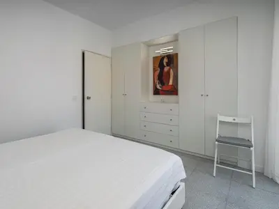 a white bedroom with a bed and a chair at Algarsol 1bdr apartment near the beach in Quarteira