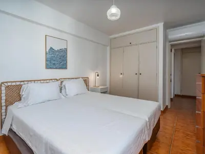 a white bedroom with a bed and a closet at T1 com Varanda e vista mar a 200m da Praia in Quarteira