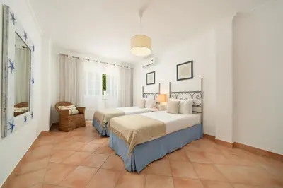 a bedroom with two beds and a chair at Charming Villa with Private Pool by LovelyStay in Albufeira