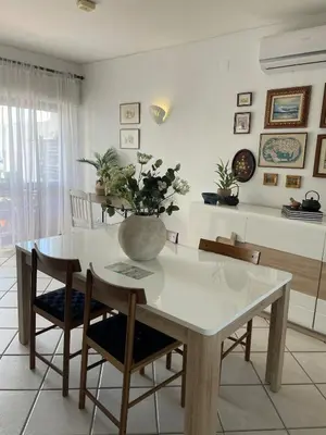 a dining room table and chairs with a vase with flowers at Oura beach & sun in Albufeira