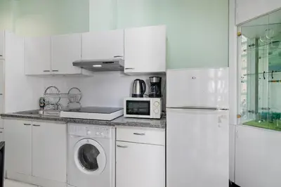 a kitchen with white cabinets and a washer and dryer at Faro Downtown Suites - Vila Adentro in Faro