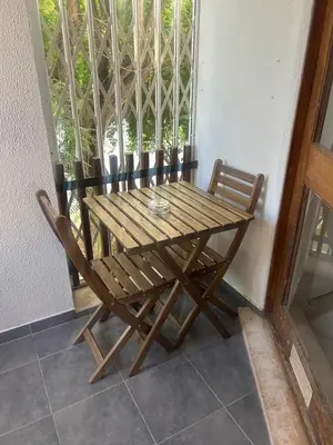 a wooden table and chair on a porch with a window at Casa Altair in Quarteira