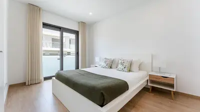 a white bedroom with a large bed and a window at Elegant 2BDR Apartment in Quarteira by Lovelystay in Quarteira