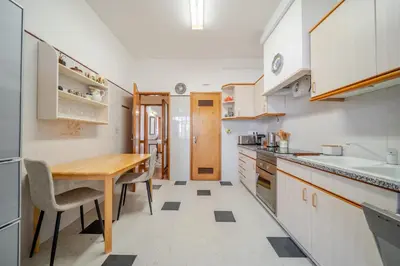 a kitchen with white cabinets and a wooden table at BeGuest Dream House in Loulé
