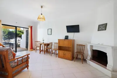 a living room with a fireplace and a table and chairs at Sol Nascente 2_vilamoura in Quarteira