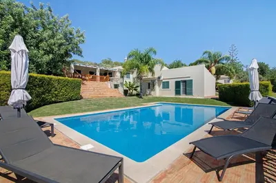 a swimming pool with two lawn chairs and umbrellas at Excelente Studio in Loulé