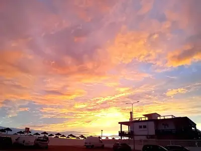 a cloudy sky with cars parked on the beach at Encanto da Ria in Faro