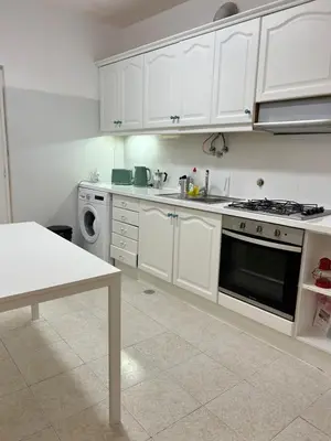 a white kitchen with a sink and a stove at Casa da Praia em Olhos de Água a 50 metros da Praia in Olhos de Água