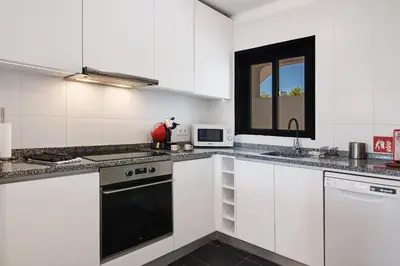a kitchen with white cabinets and a black appliance at Kyara House in Albufeira