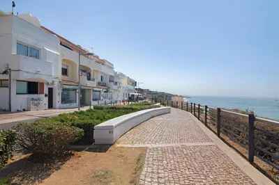 a sidewalk next to the ocean next to a building at Mar à Vista in Albufeira
