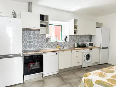 a kitchen with white cabinets and a washer and dryer at Sao Pedro Guest House in Faro