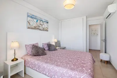 a bedroom with a bed with a purple comforter at Paraná in Quarteira