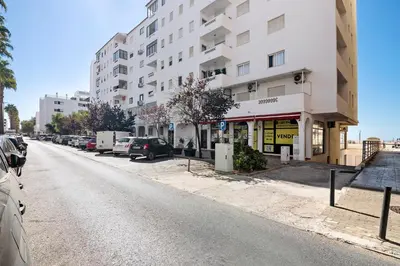 an empty street with cars parked in front of a building at Paraná in Quarteira