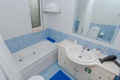 a blue tiled bathroom with a sink and a tub and a toilet at Ver o Mar in Albufeira